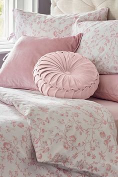 a bed with pink and white comforters, pillows and blankets on top of it