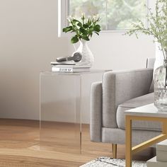 a living room with a couch, coffee table and vase on the end table in front of a window