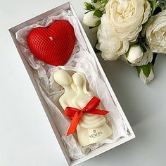 two soaps in a gift box with roses and a bouquet of white flowers behind them