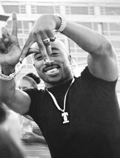 a black and white photo of a man making the v sign with his hands in front of him