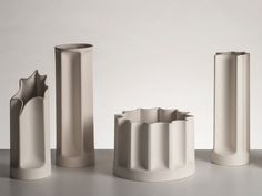 three tall white vases sitting next to each other on top of a gray table