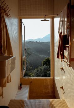 a bathroom with a large window looking out onto the hills outside at sunset or sunrise