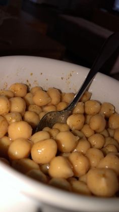 a white bowl filled with lots of food and a spoon sticking out of the top