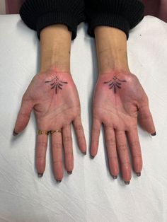 two hands with small tattoos on them