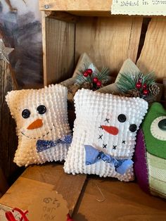 three snowman pillows sitting on top of a wooden box next to a christmas tree