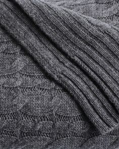 a close up view of the back of a gray knitted sweater with two rows of cables