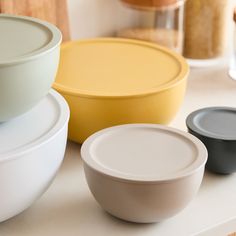 three different colored bowls sitting on top of a counter next to some bread tins