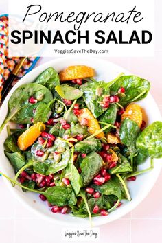 a white bowl filled with spinach salad and topped with pomegranate