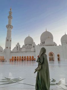 a woman standing in front of a white building with many arches and minarets