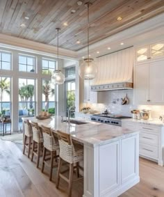 a large kitchen with white cabinets and wooden floors, along with an island in the middle