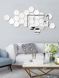 a living room filled with white furniture and mirrors on the wall above it's coffee table