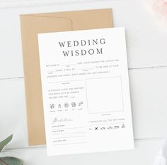 a wedding wish card on top of a brown envelope next to a pink flower and greenery