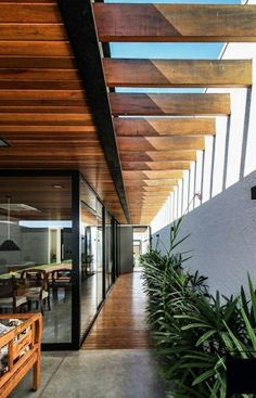 the inside of a modern house with wood and glass on the roof, along with plants