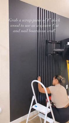 a woman sitting on a chair in front of a black wall with words written on it