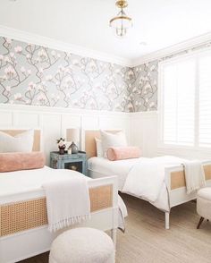 two beds in a bedroom with floral wallpaper on the walls and white bedding