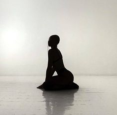 a woman is sitting on the floor with her back to the camera and looking at something in the distance