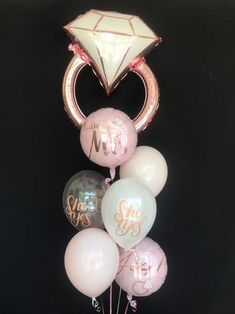 a vase filled with lots of balloons in front of a black background and some gold foil lettering