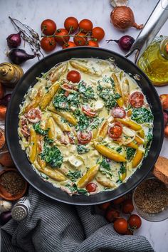 a pan filled with pasta and vegetables on top of a table next to other ingredients