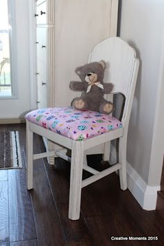 a teddy bear sitting on top of a white chair next to a doorway with wooden floors