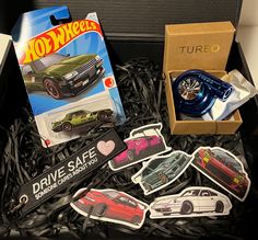 a box filled with different types of diecast cars and stickers next to a watch