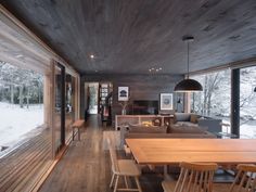 a dining room and living room with wood flooring in the snow covered forest area