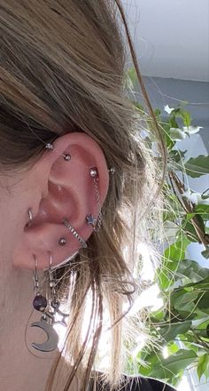 a close up of a person with ear piercings on their ears and behind them is a tree