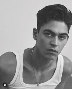 black and white photograph of a young man wearing a tank top with his hand on his hip