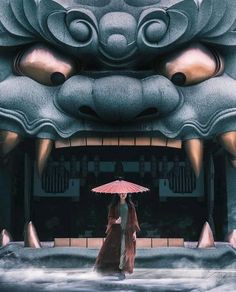 a woman with an umbrella walking in front of a dragon statue