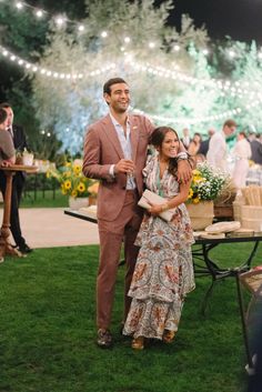 a man and woman standing next to each other in front of a table with flowers on it