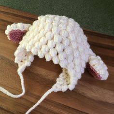 a white crocheted hat sitting on top of a wooden floor