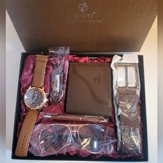 an open box containing a watch, pen, and glasses with other items in it