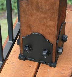 the back end of a wooden bench with black iron brackets on it's sides