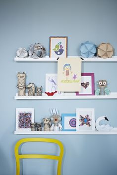 two white shelves with pictures and other items on them in a child's room