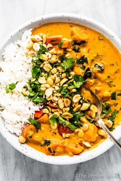 a white bowl filled with rice, beans and greens next to a spoon in it