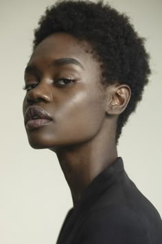 a woman with short hair wearing a black shirt and looking off to the side in profile