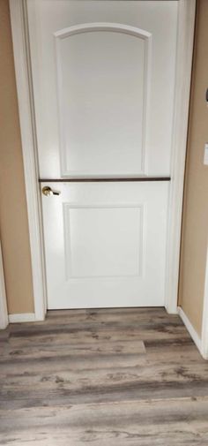 an empty room with a white door and wood flooring on the side of it