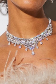 a close up of a woman wearing a necklace and earring on her neck with feathers