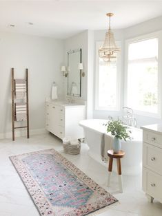 a white bathroom with a rug, sink and bathtub in the middle of it