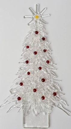 a glass christmas tree with red and white balls on it's base, hanging from the wall