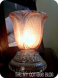 a glass vase sitting on top of a wooden table next to a framed photo with the words, the ivy cottage blog