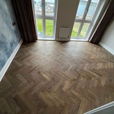 an empty room with wood flooring and large open window overlooking the street outside it