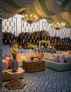 an outdoor seating area with chandeliers and pillows