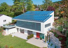 an aerial view of a modern house with solar panels on the roof and in the yard