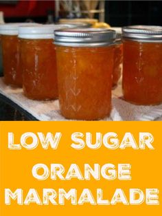 four jars of orange marmalade sitting on top of a counter with the words low sugar orange marmalade