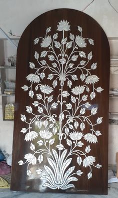 an intricately designed wooden door with white flowers and leaves painted on the outside side