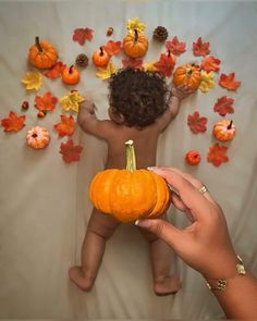 a person holding a pumpkin in front of a baby