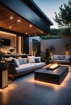 an outdoor living area with couches, tables and lights