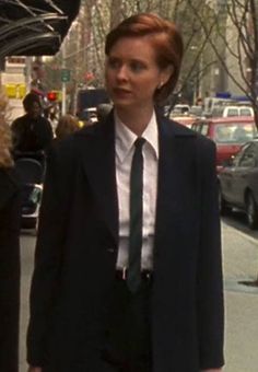 a woman in a suit and tie walking down the street