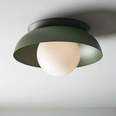 a green and white light hanging from the ceiling in a room with no one around it