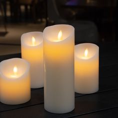 three lit candles sitting on top of a wooden table